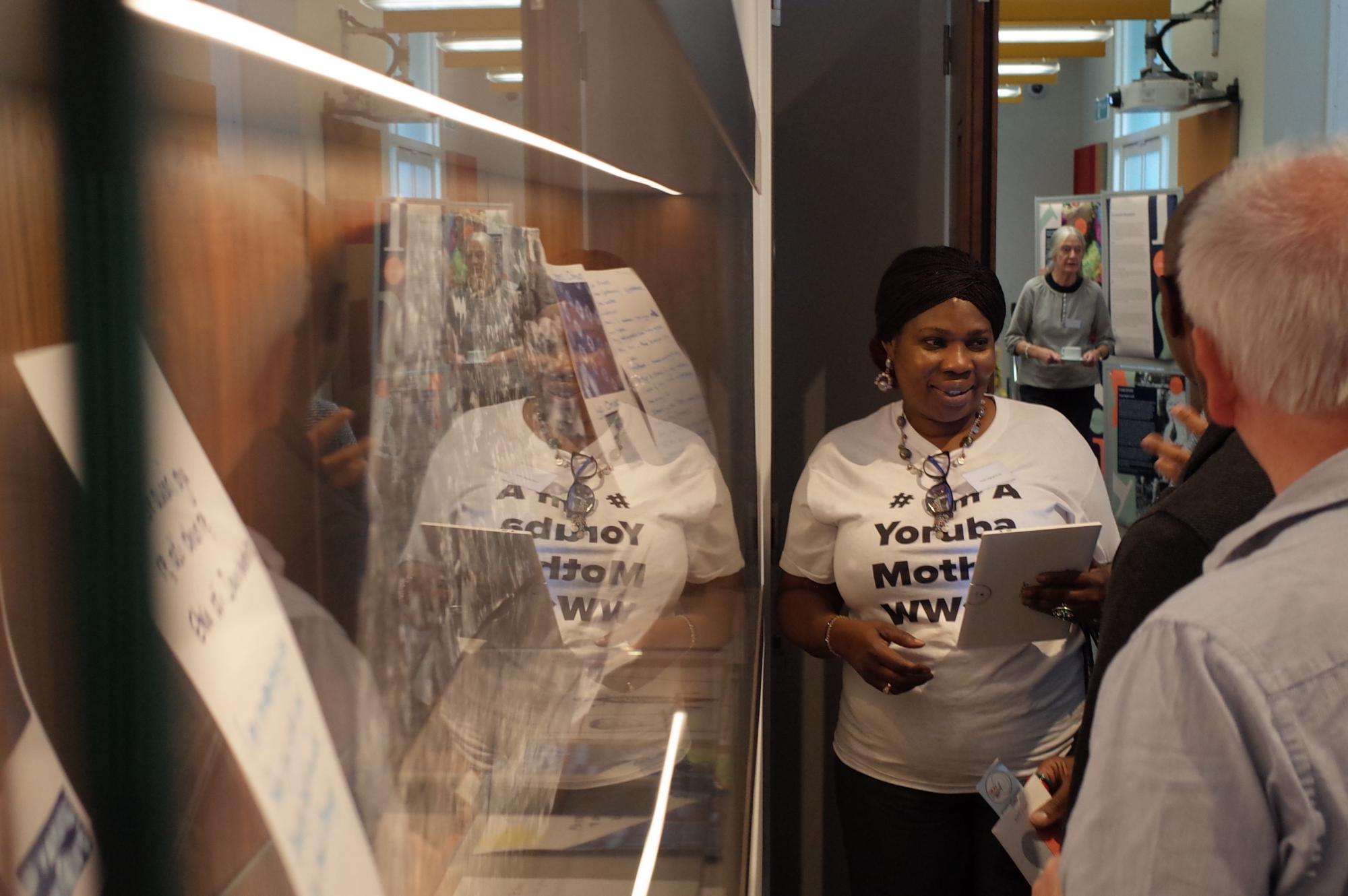 Delegates talk in front of a dispaly case showcasing community group contributions to the Motherhood, Loss and the First World War project