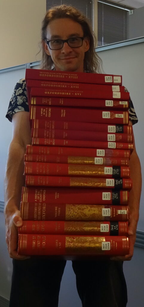 The complete run - to date - of the Victoria County History of Oxfordshire. A pile of 18 large red books.
